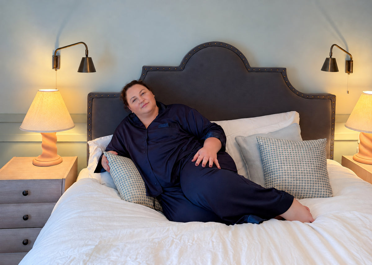 Philippa wearing navy Hebe Tencel pyjamas on a bed